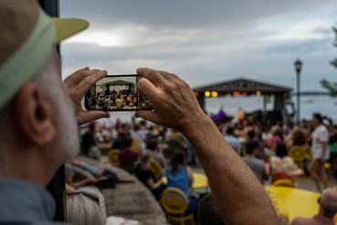 Attendee in the audience filming Jazz Fest on their smartphone