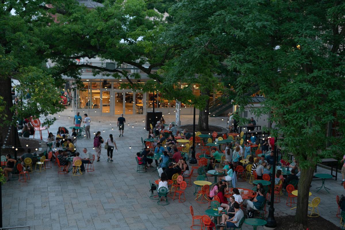 Looking down through the trees at the Terrace, people sitting at tables and chairs under string lights