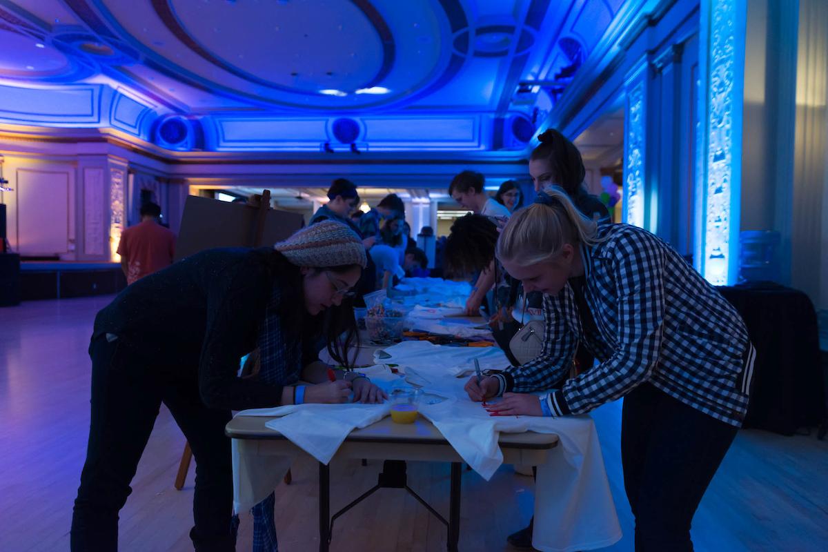 Students write on t-shirts at a WUD Lit Totally 80s Party