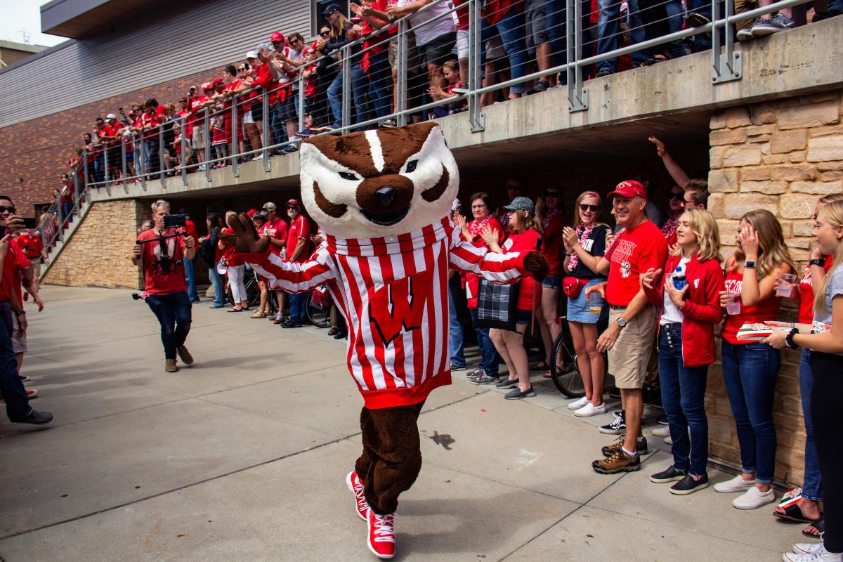 Bucky walking toward camera with Badger Bash crowd around him applauding.